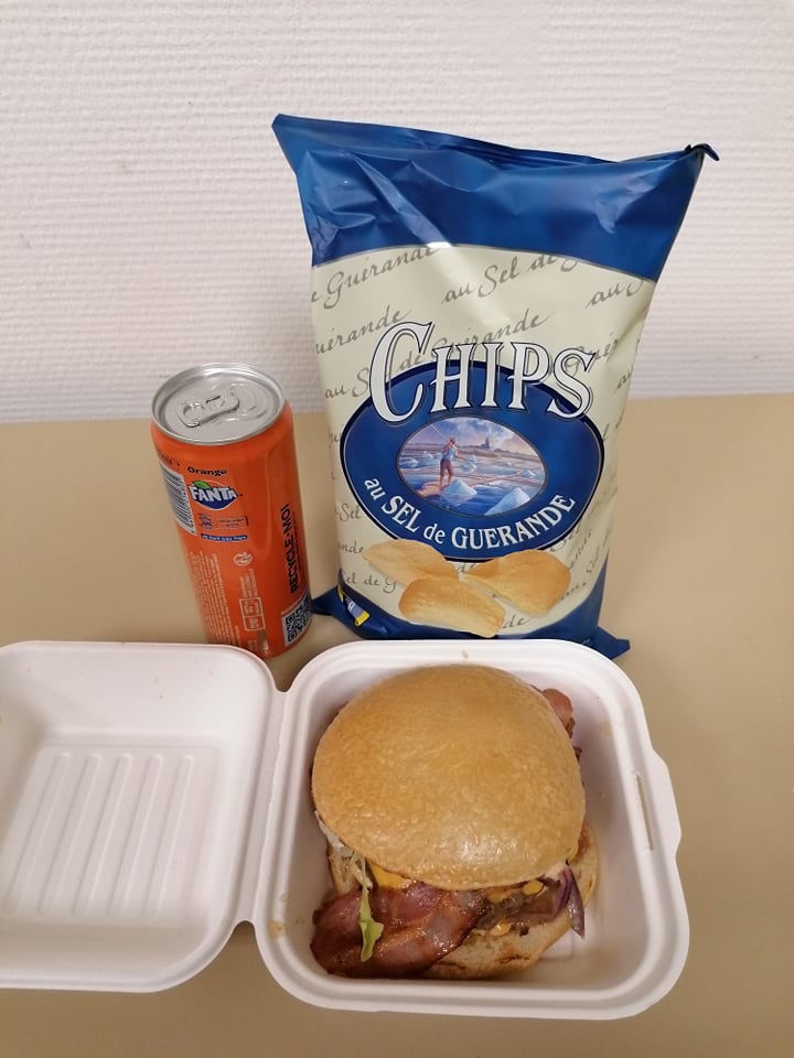Burger appétissant servi avec un paquet de chips et une boisson gazeuse